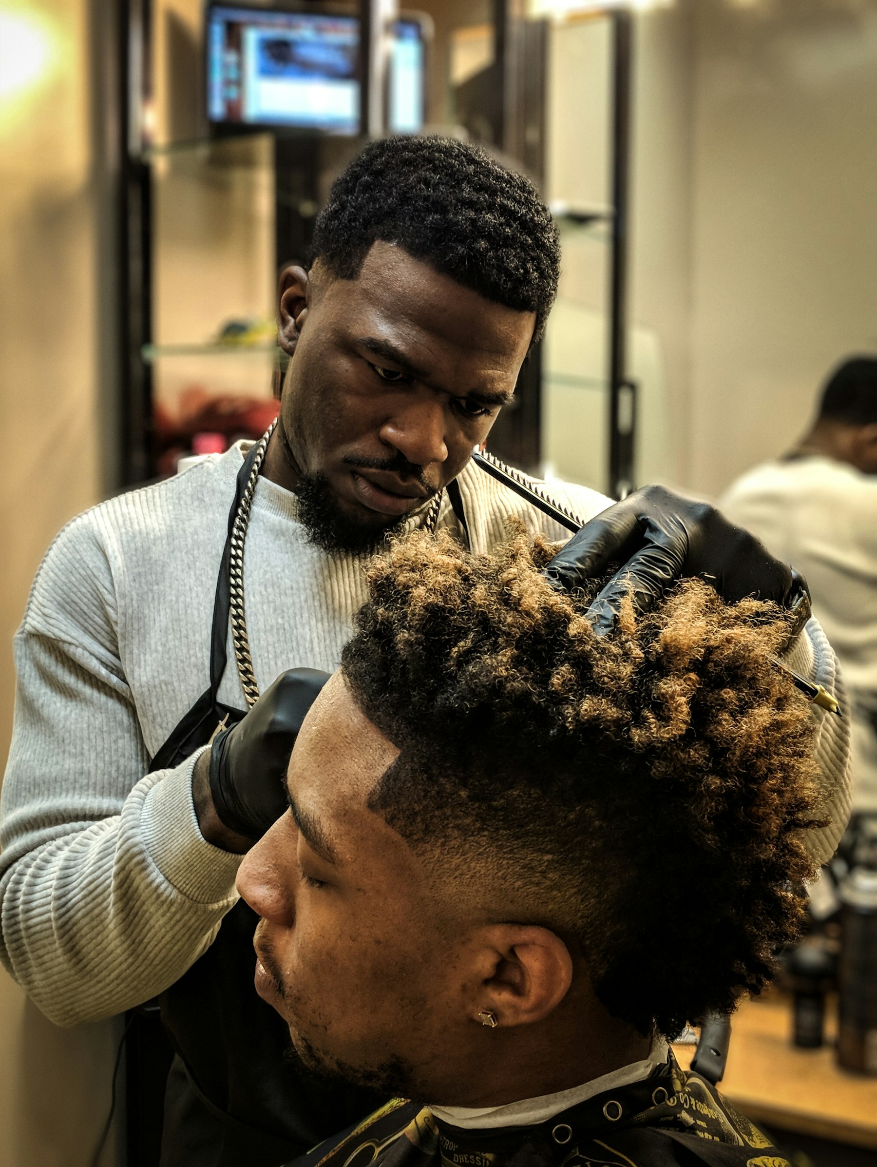 A barber mid-fade on a client with a curly top — reference photo, not T-Low's actual work