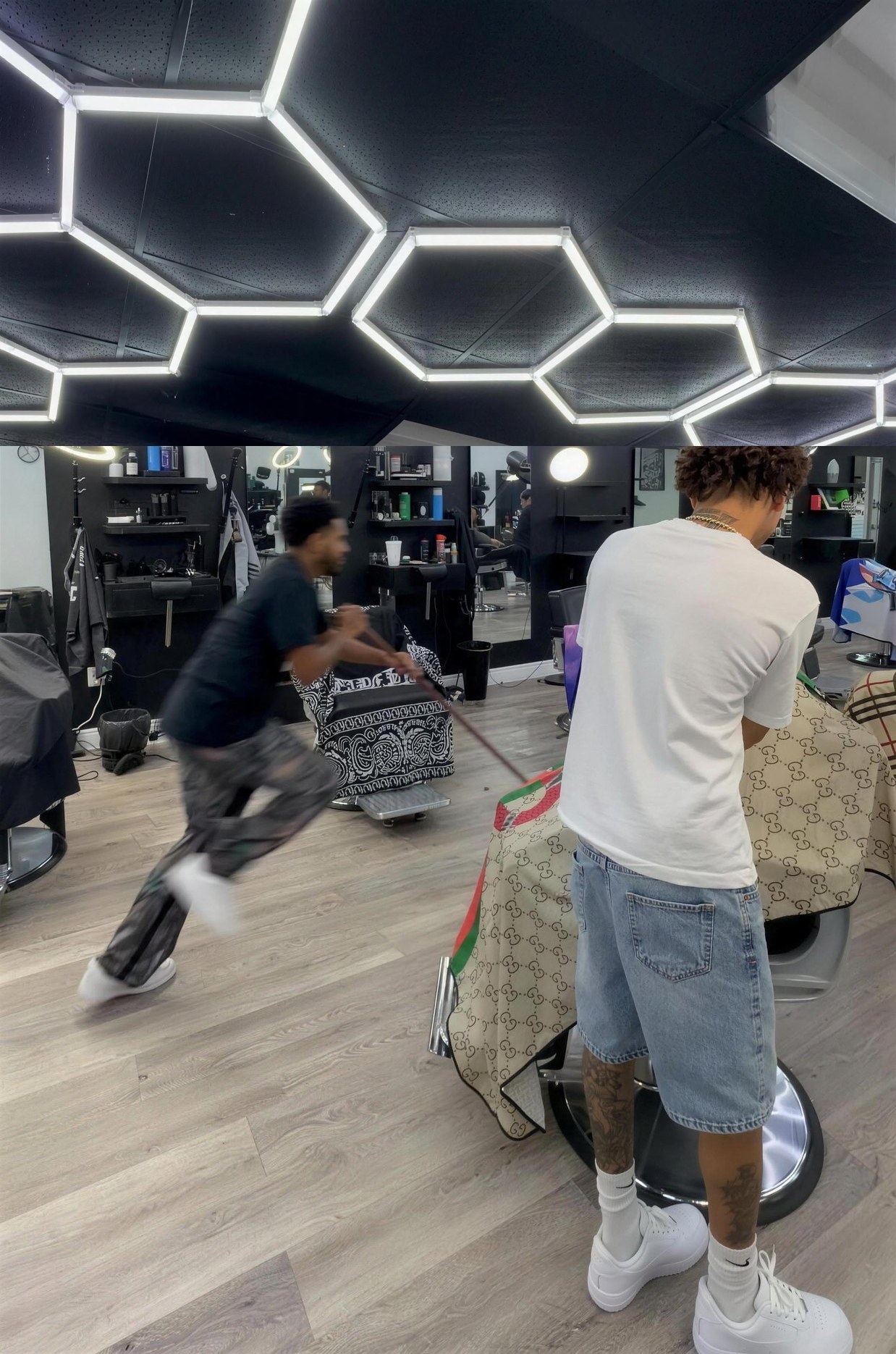 Real interior of Plugged In Barbershop 410 — hexagon LED ceiling, two barbers working